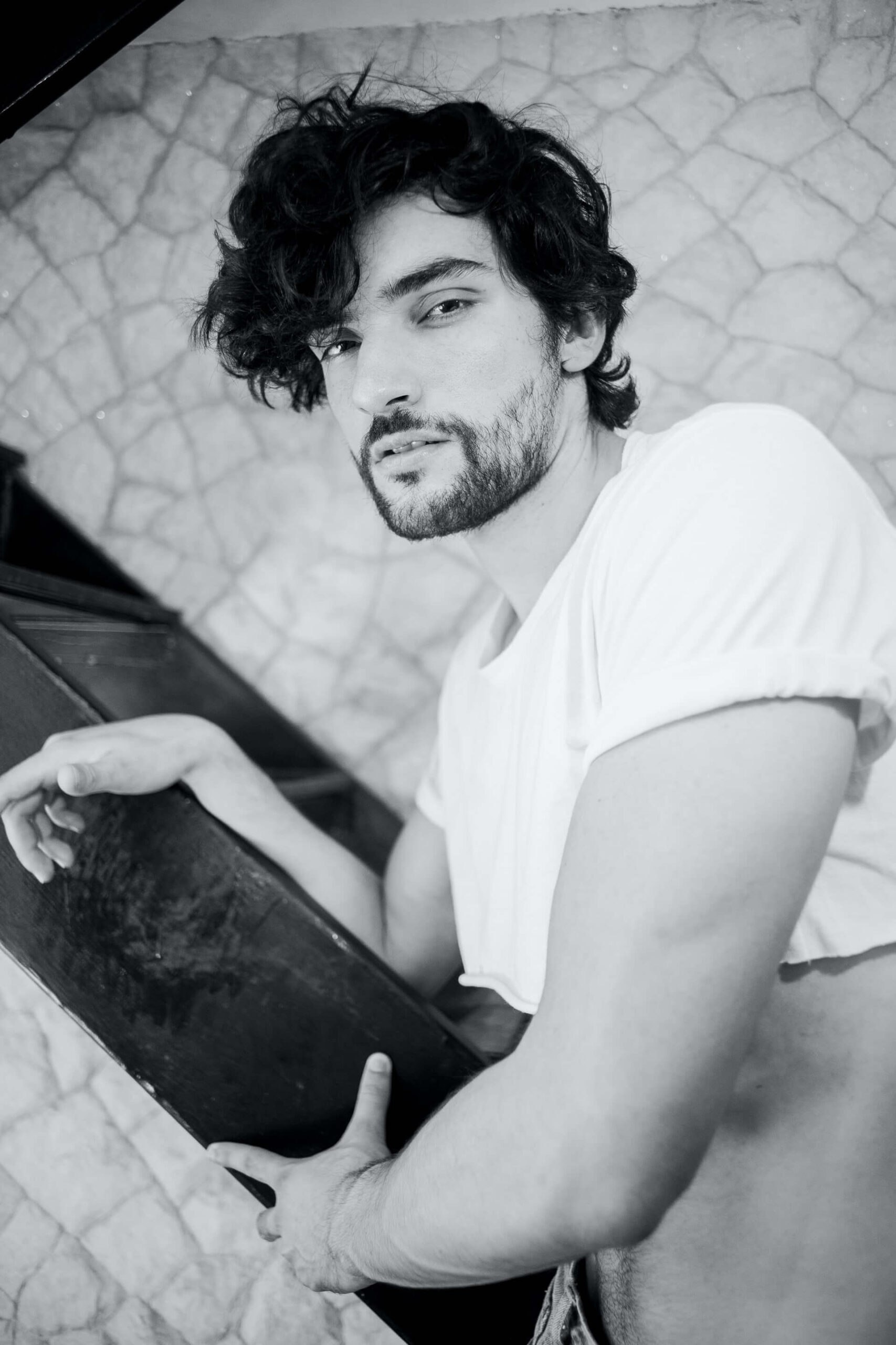 Lean man with wavy hair and croptop facing camera