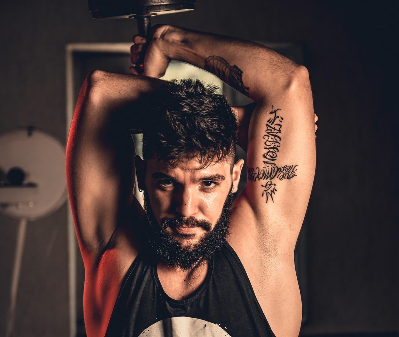 Bearded man lifting dumbbell over head
