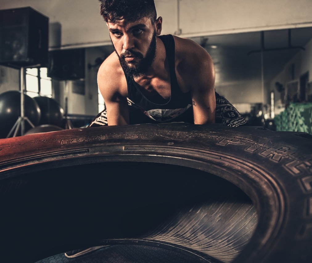 Bearded man lifting vehicle tire