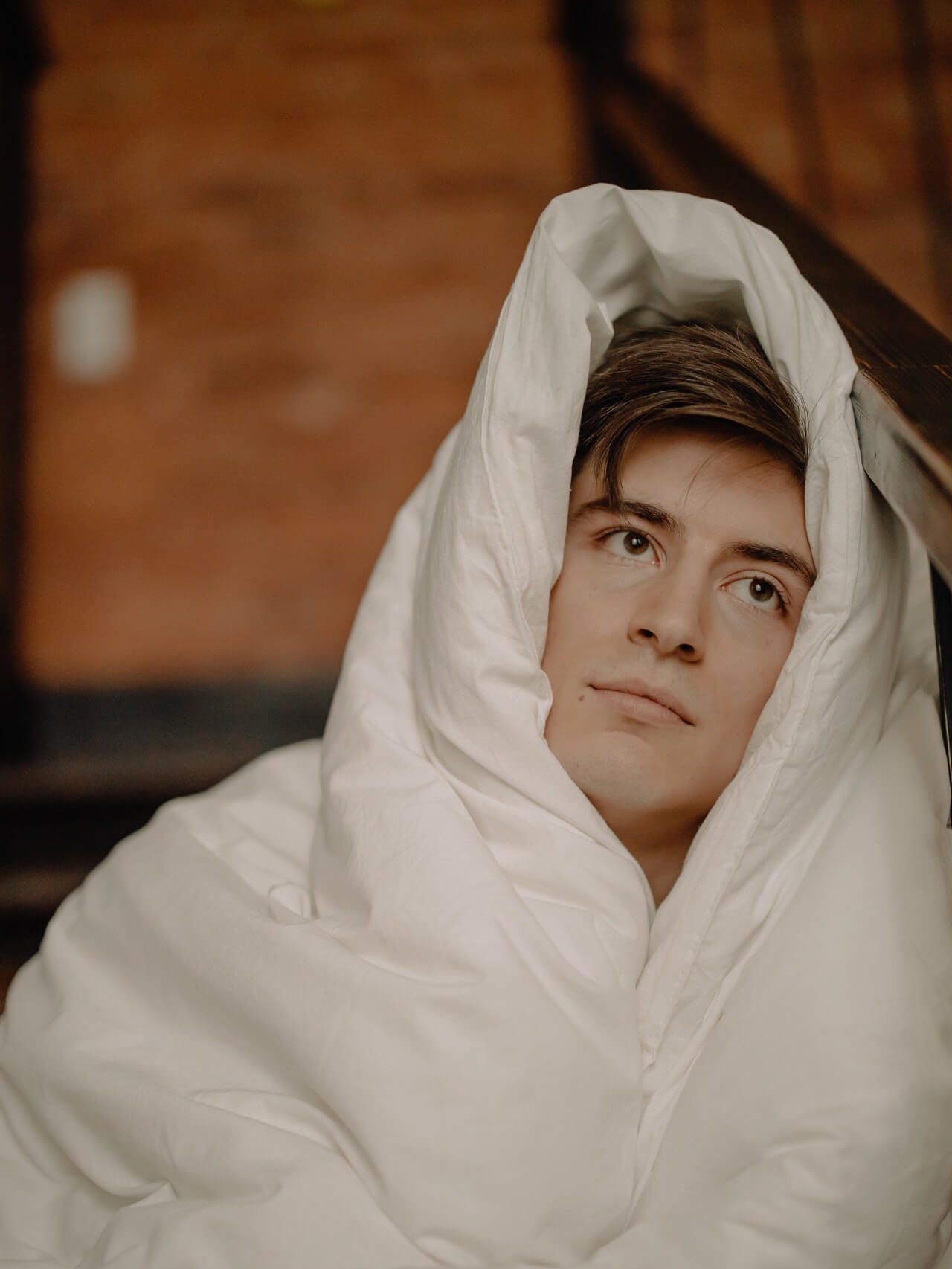 Headshot of young man in white blanket