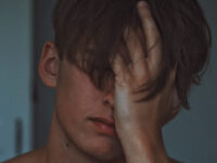 Headshot of man covering face with hand
