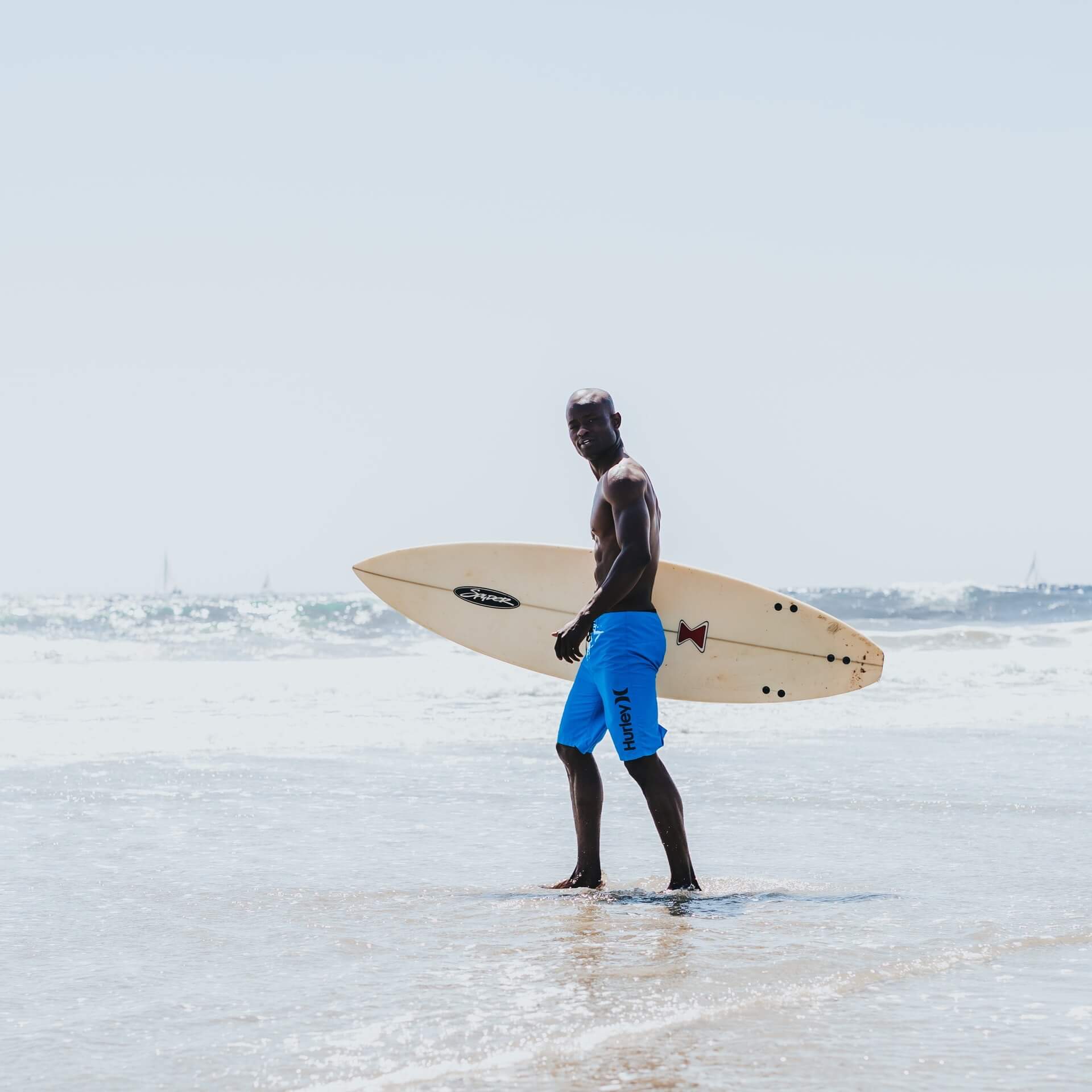 Shirtless surfer walking in water