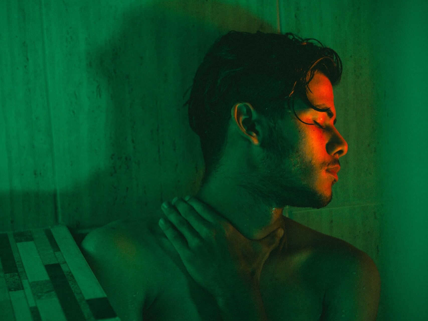 Man holding neck with eyes closed in sauna